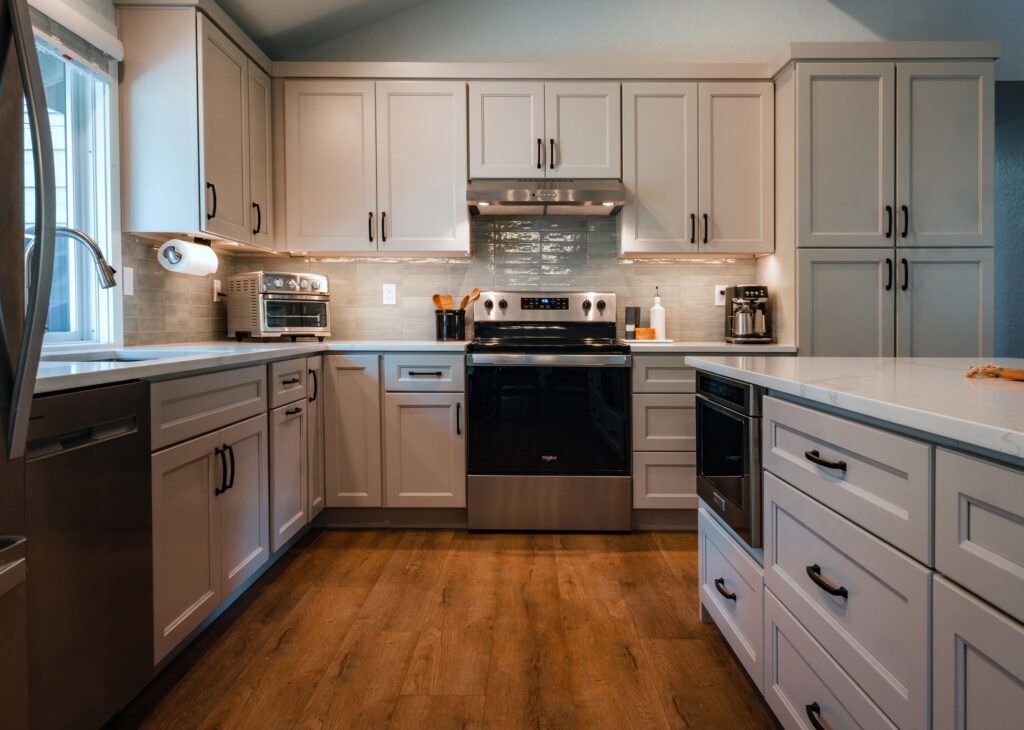Edmonds kitchen, with a clear view of the drawers on the island, a black and silver range, and a backsplash featuring grey tile.