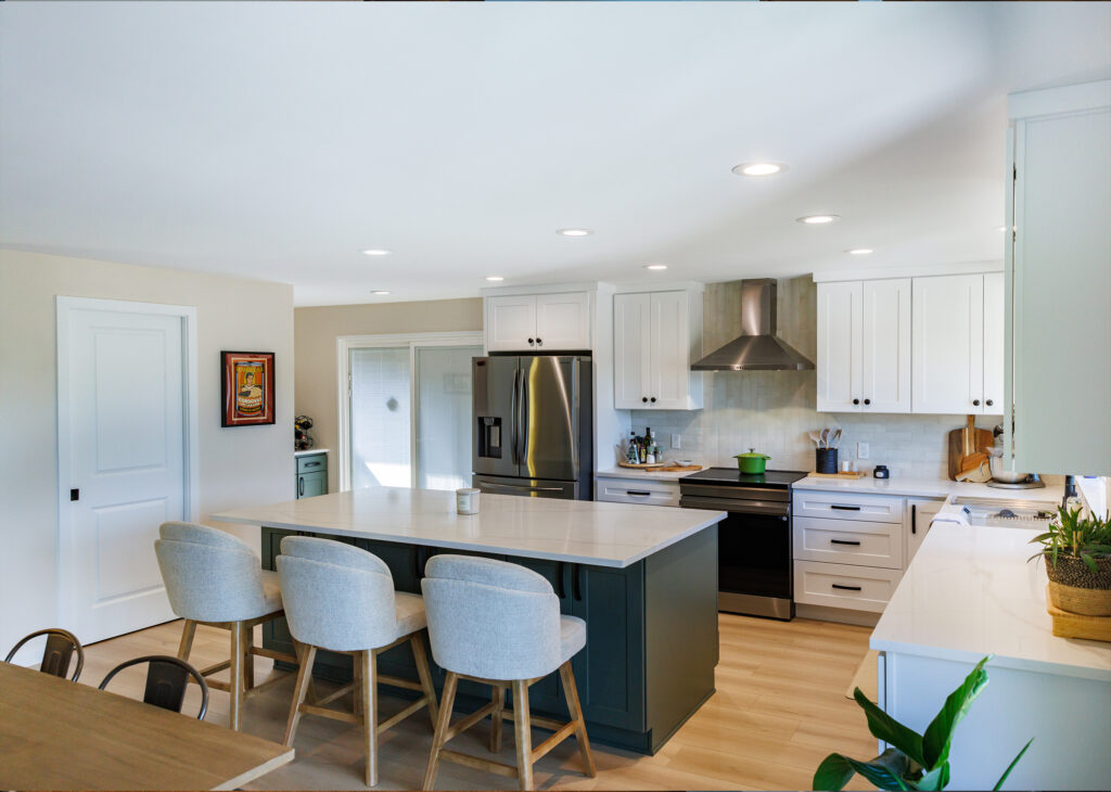 Remodeled kitchen in Everett, WA by JL Remodeling with white shaker cabinets, a dark green island with quartz countertop and extended seating area, upholstered barstools, and stainless steel appliances.
