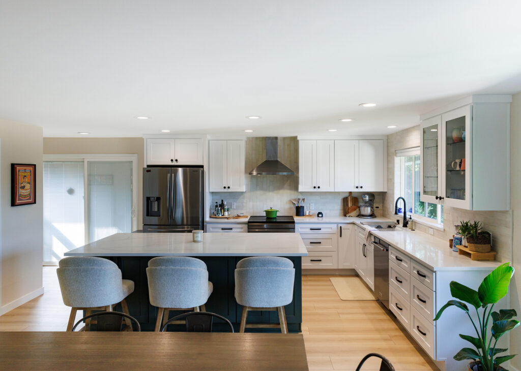 Everett, WA kitchen renovation featuring an L-shaped layout, white shaker cabinetry, quartz counters, and a green island with an extended seating area.