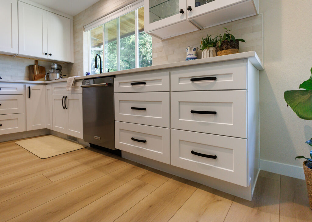 Close-up of white shaker drawer cabinetry with black bar pulls and a stainless steel dishwasher in an Everett, WA kitchen remodel.